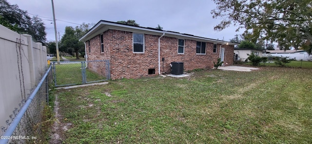 rear view of house featuring central AC and a yard