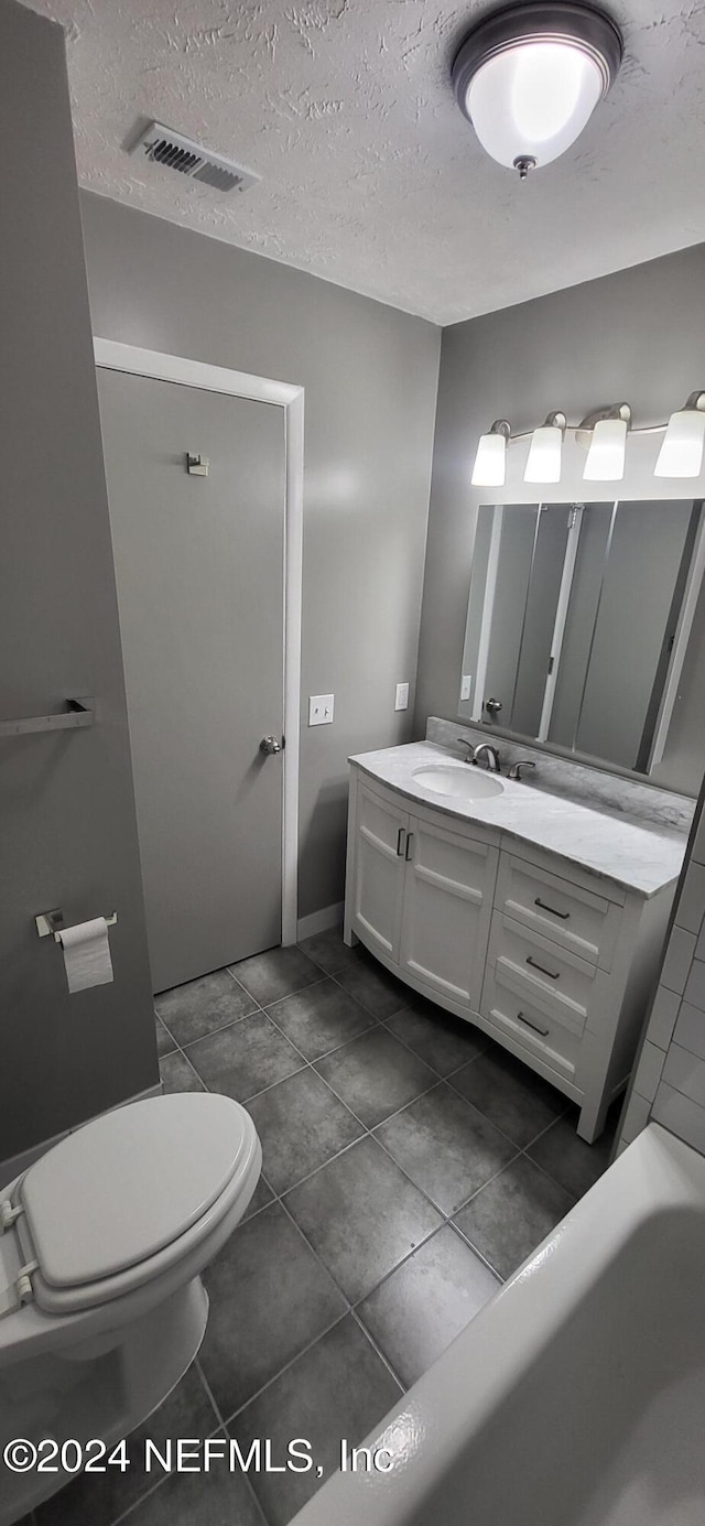 bathroom with a washtub, a textured ceiling, vanity, and toilet