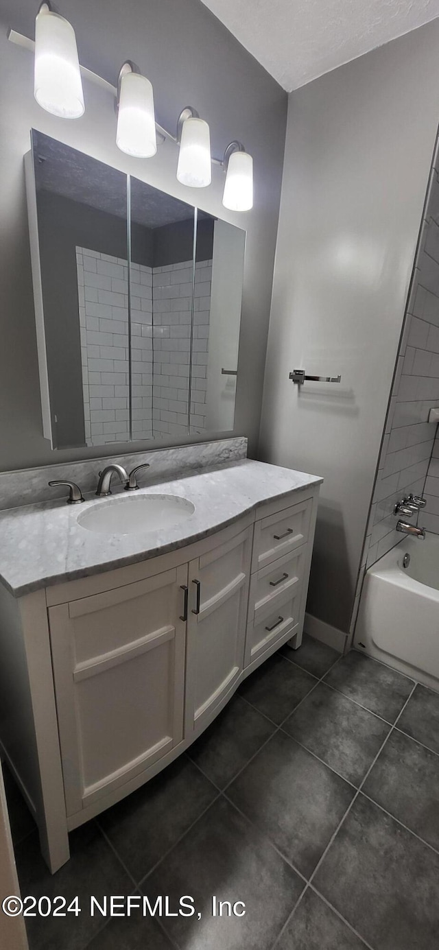 bathroom with tile patterned floors, vanity, and tiled shower / bath