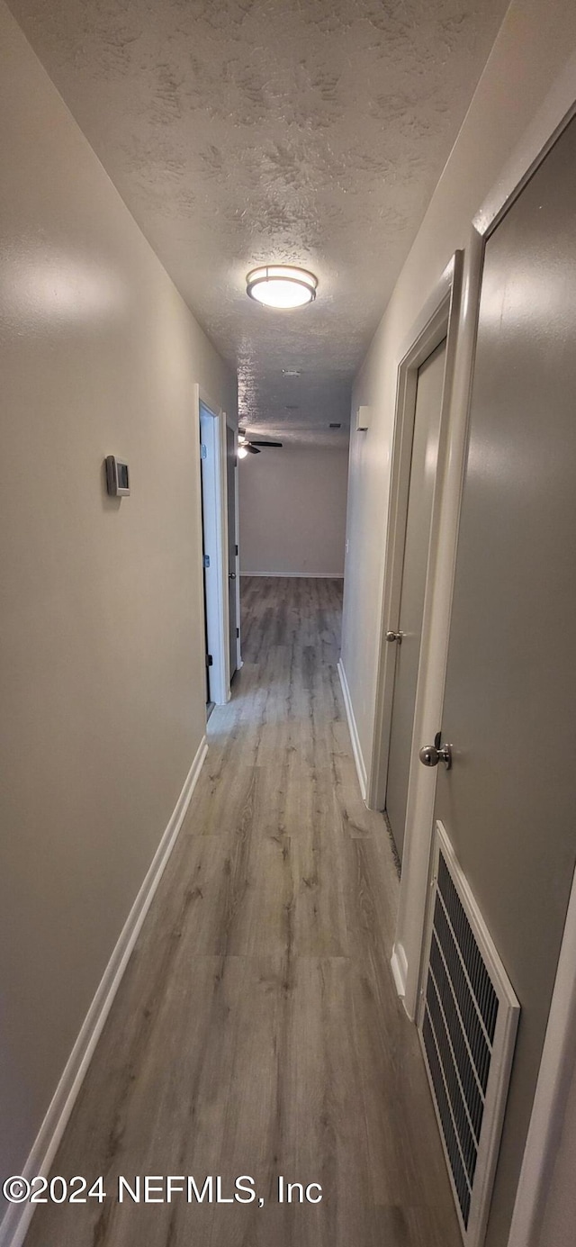 hallway featuring a textured ceiling and hardwood / wood-style flooring