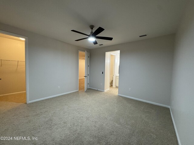 unfurnished bedroom with ceiling fan, a closet, a spacious closet, and connected bathroom