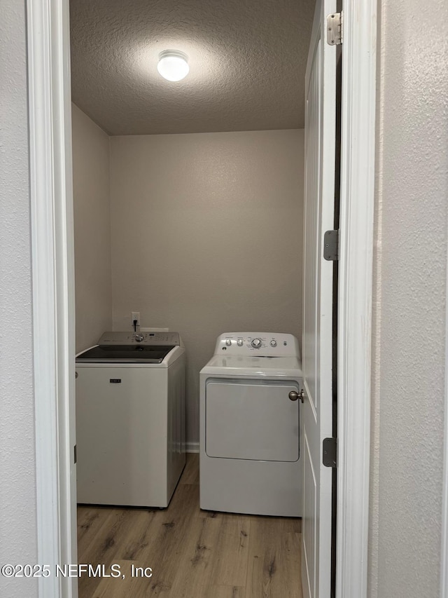 washroom featuring washer and dryer, a textured ceiling, and light hardwood / wood-style flooring