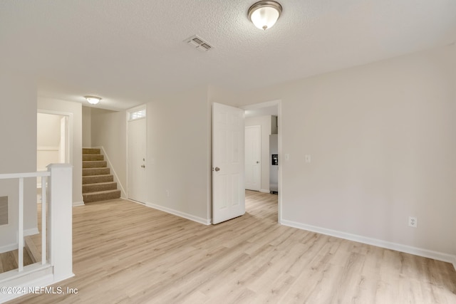 unfurnished room with a textured ceiling and light wood-type flooring