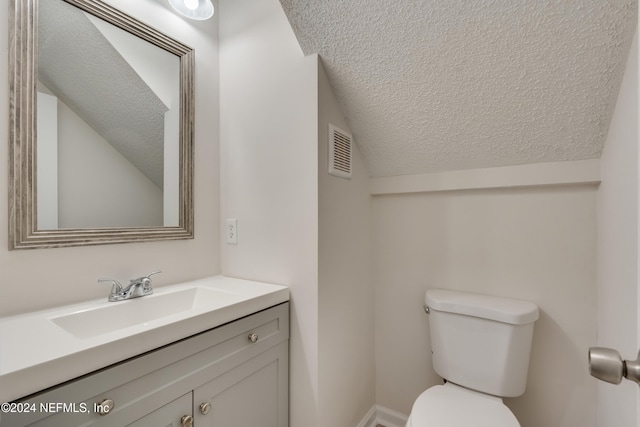 bathroom with a textured ceiling, vanity, toilet, and lofted ceiling