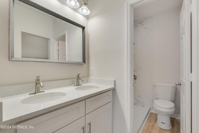 bathroom with tiled shower, hardwood / wood-style floors, vanity, and toilet