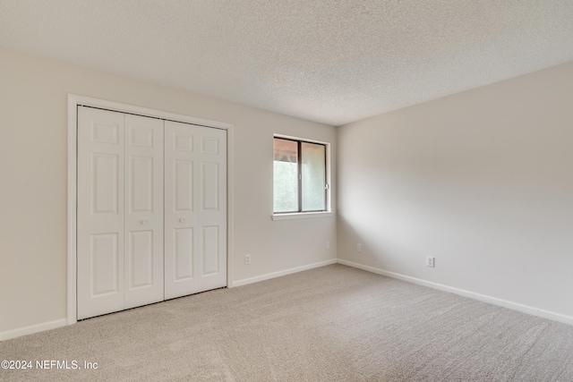 unfurnished bedroom featuring a closet, light colored carpet, and a textured ceiling