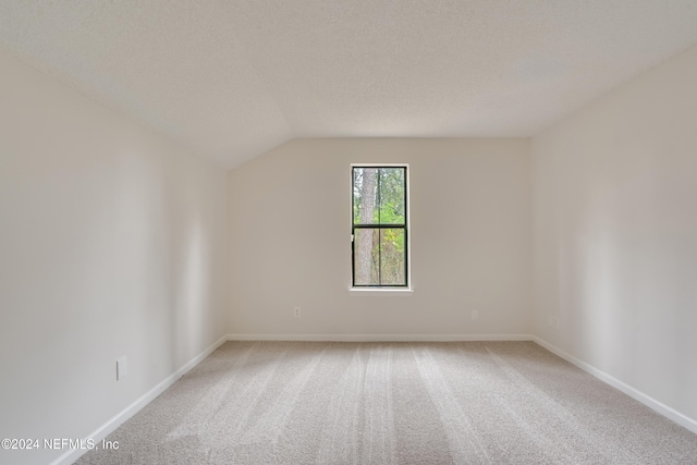 carpeted empty room featuring a textured ceiling and lofted ceiling