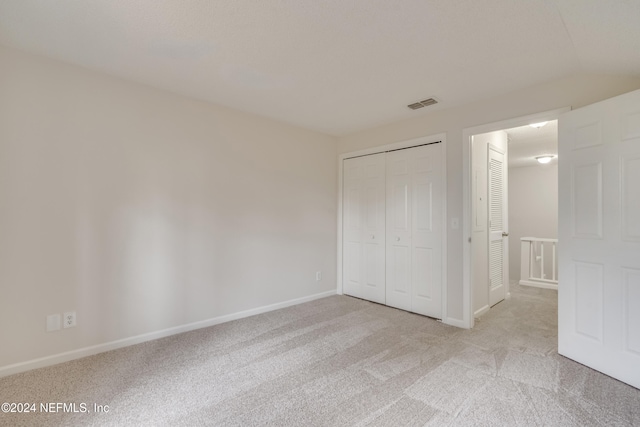 unfurnished bedroom featuring light colored carpet and a closet