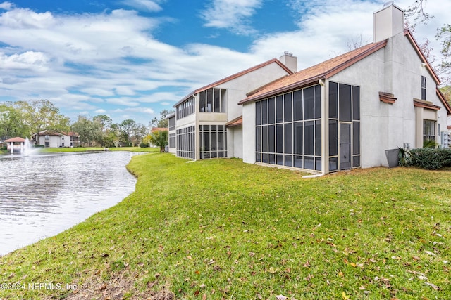 back of house featuring a sunroom, a water view, and a yard