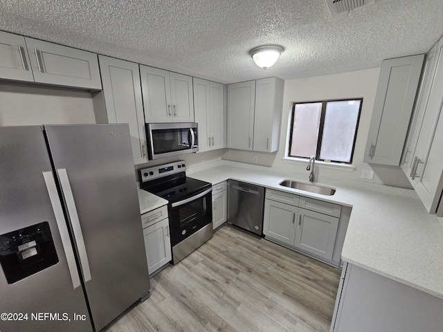 kitchen featuring gray cabinetry, sink, stainless steel appliances, and light hardwood / wood-style flooring