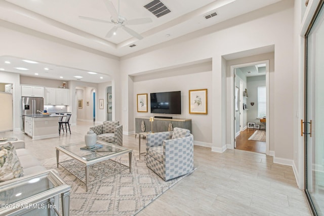 living room featuring a raised ceiling and ceiling fan