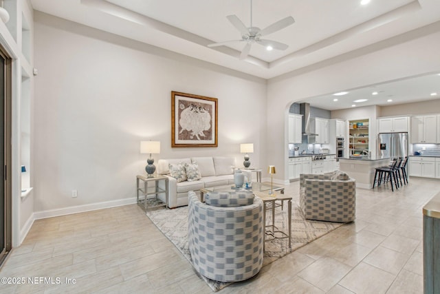 living room with ceiling fan and a tray ceiling