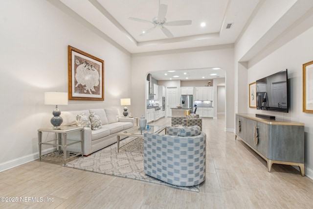 living room with ceiling fan and a raised ceiling