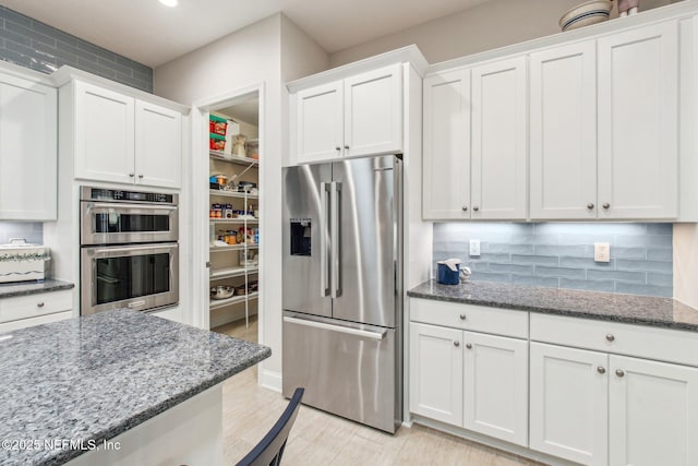 kitchen featuring dark stone countertops, white cabinetry, and appliances with stainless steel finishes