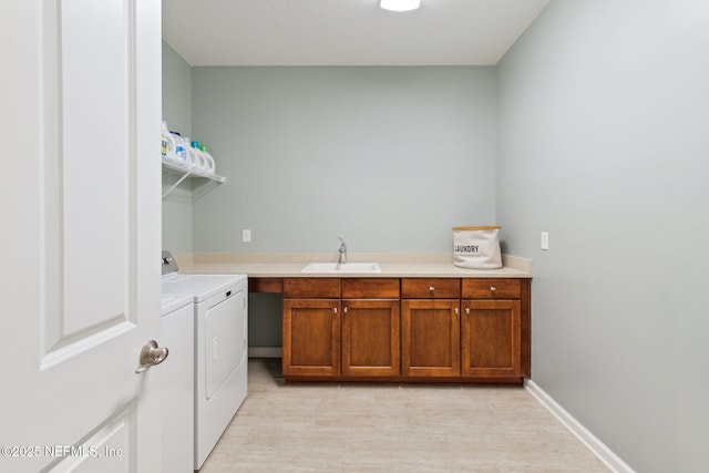 clothes washing area featuring separate washer and dryer, sink, and cabinets