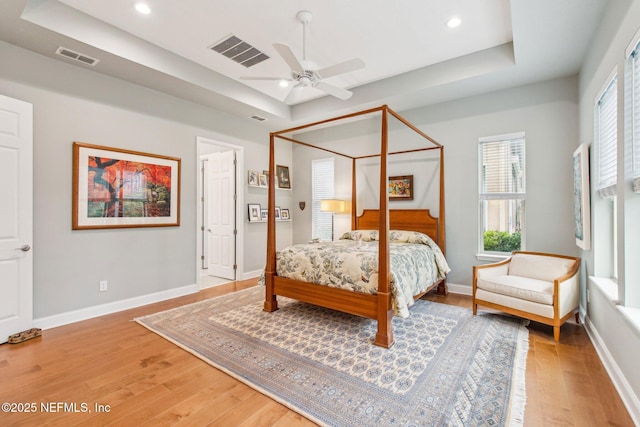 bedroom featuring a raised ceiling, ceiling fan, and hardwood / wood-style flooring