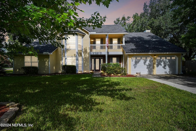 front facade with a balcony, a garage, and a lawn