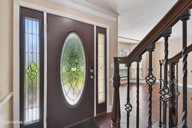 entryway with dark hardwood / wood-style flooring, ornamental molding, and a textured ceiling