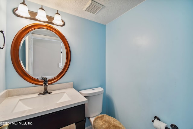 bathroom featuring vanity, toilet, and a textured ceiling