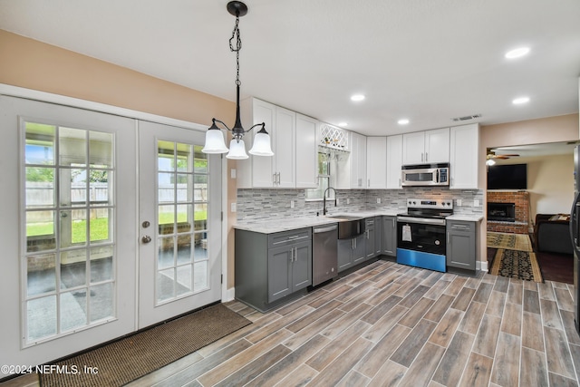 kitchen with appliances with stainless steel finishes, gray cabinets, white cabinetry, and pendant lighting