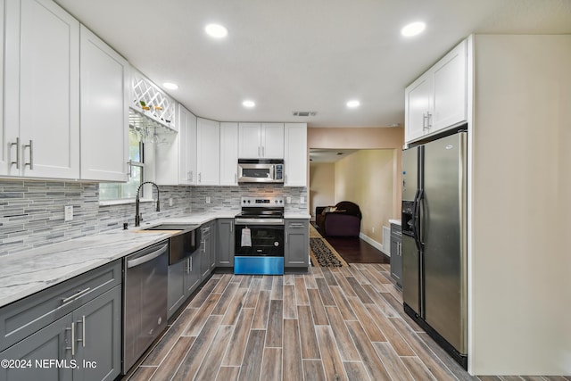 kitchen with gray cabinetry, white cabinets, sink, decorative backsplash, and stainless steel appliances