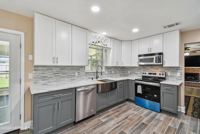 kitchen with gray cabinets, white cabinetry, sink, and stainless steel appliances