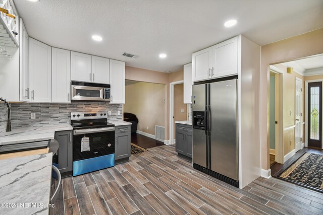 kitchen featuring gray cabinets, light stone counters, white cabinets, and appliances with stainless steel finishes