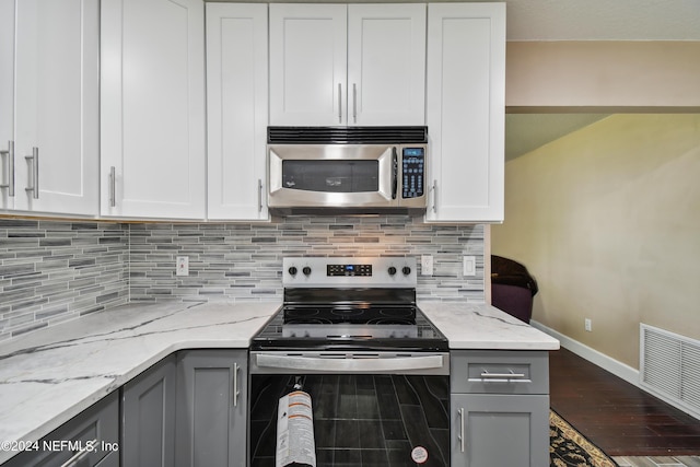 kitchen featuring light stone countertops, stainless steel appliances, white cabinetry, and gray cabinetry