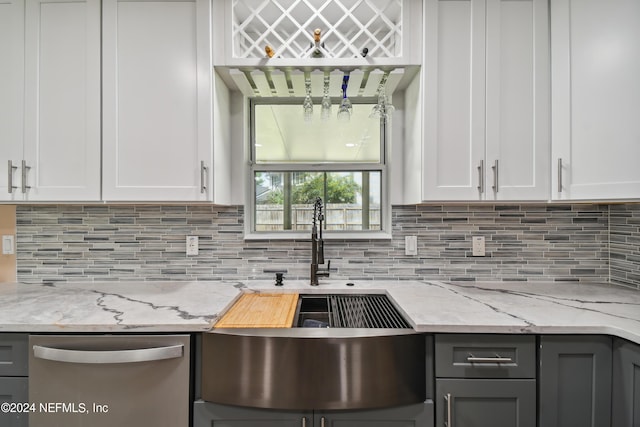 kitchen featuring dishwasher, sink, decorative backsplash, light stone countertops, and white cabinetry