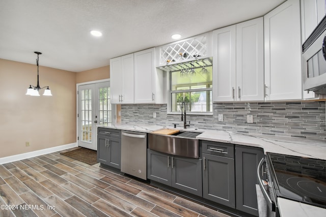 kitchen featuring french doors, black / electric stove, stainless steel dishwasher, white cabinetry, and hanging light fixtures