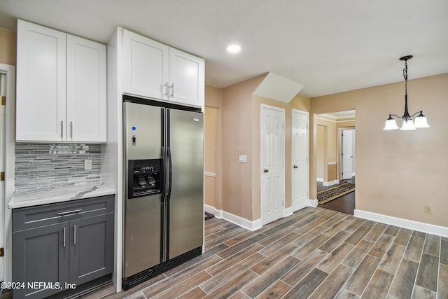 kitchen featuring stainless steel fridge, tasteful backsplash, decorative light fixtures, an inviting chandelier, and white cabinetry