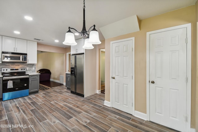 kitchen featuring gray cabinetry, white cabinetry, dark wood-type flooring, backsplash, and appliances with stainless steel finishes