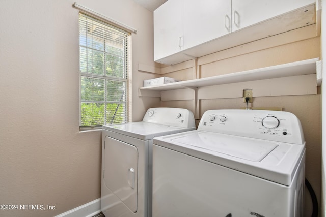 laundry room featuring cabinets, independent washer and dryer, and a healthy amount of sunlight