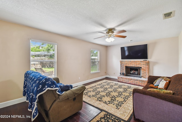 living room with wood-type flooring, plenty of natural light, ceiling fan, and a brick fireplace