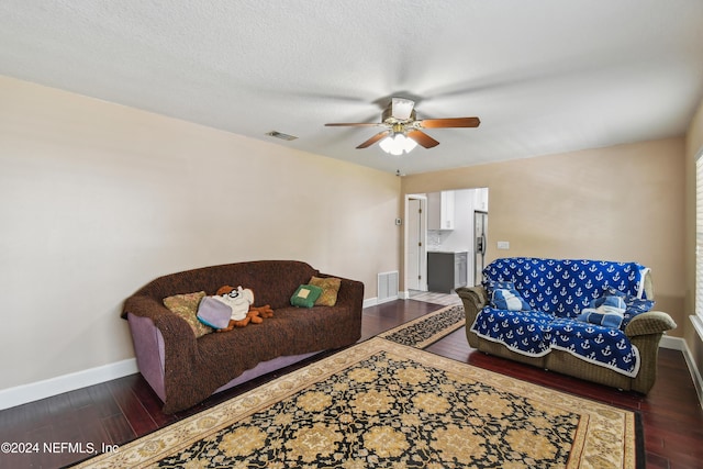 living room with ceiling fan, dark hardwood / wood-style flooring, and a textured ceiling