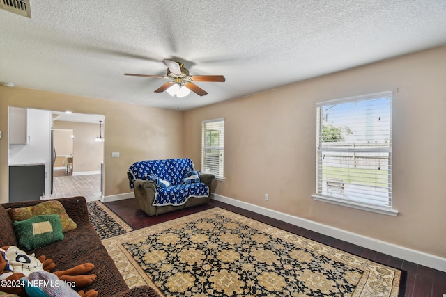 sitting room with wood-type flooring, a textured ceiling, ceiling fan, and a healthy amount of sunlight