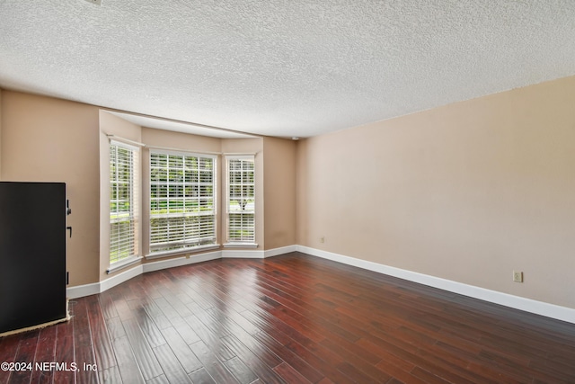 spare room featuring dark hardwood / wood-style flooring and a textured ceiling