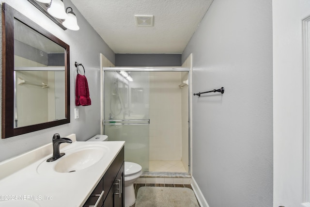 bathroom featuring a shower with door, vanity, a textured ceiling, and toilet