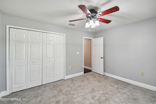 unfurnished bedroom with ceiling fan, light colored carpet, a textured ceiling, and a closet