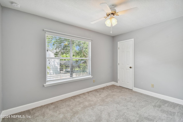 spare room with ceiling fan and light colored carpet