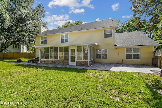 rear view of property with a lawn, a patio area, and a sunroom