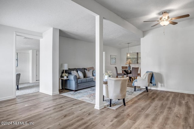 living room featuring ceiling fan, hardwood / wood-style floors, and a textured ceiling