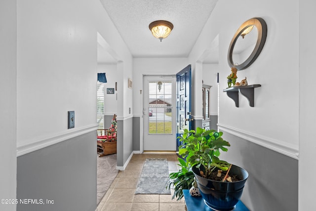 entryway with light tile patterned floors and a textured ceiling