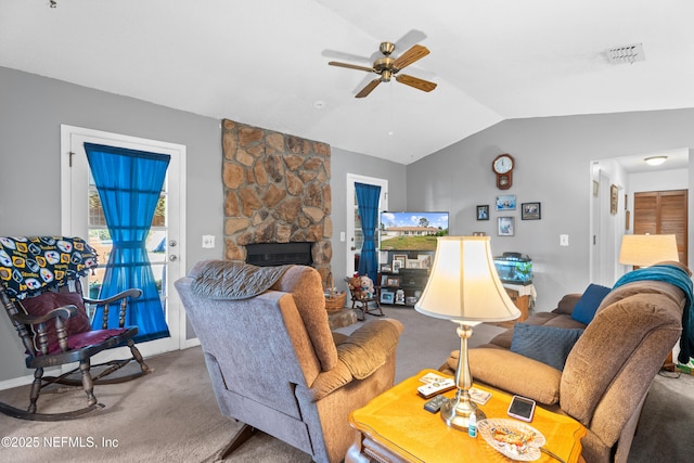 carpeted living room featuring ceiling fan, a stone fireplace, and vaulted ceiling