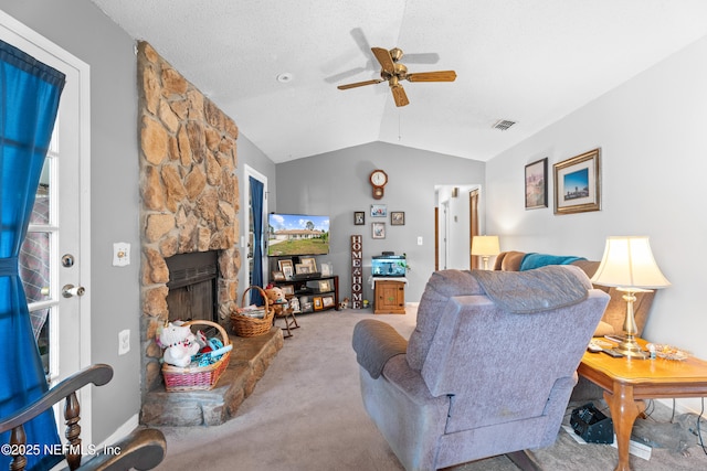 living room featuring ceiling fan, a stone fireplace, carpet floors, a textured ceiling, and vaulted ceiling