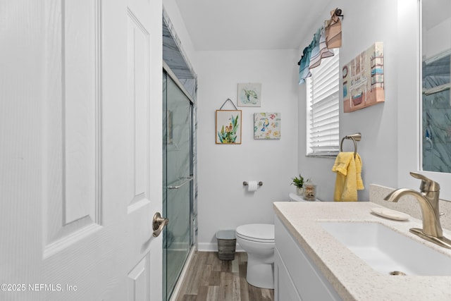 bathroom with hardwood / wood-style floors, vanity, an enclosed shower, and toilet