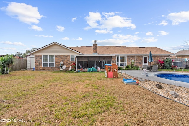 back of property featuring central AC unit, a patio area, a sunroom, a fenced in pool, and a lawn