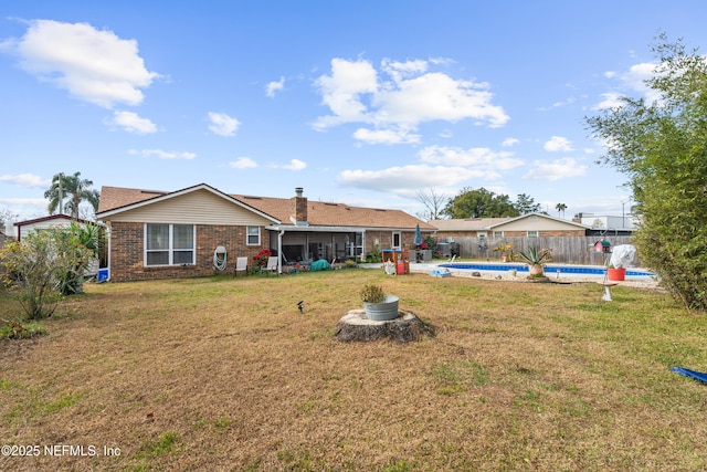 rear view of house with a fenced in pool, a lawn, and a sunroom