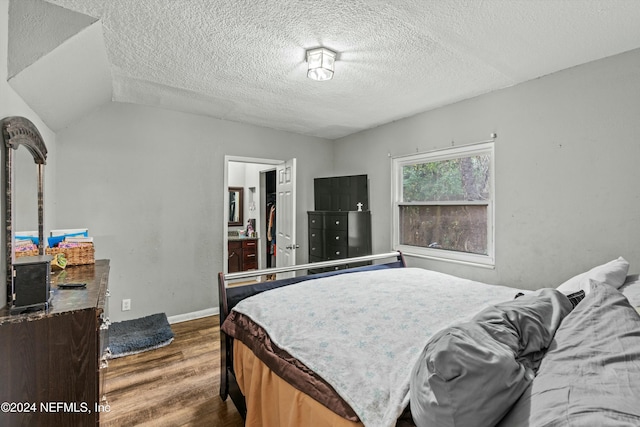 bedroom featuring a textured ceiling, dark hardwood / wood-style floors, and vaulted ceiling