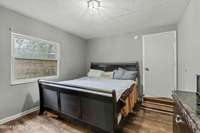 bedroom with dark wood-type flooring and a textured ceiling